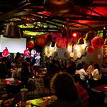一群人聚集在Full Sail的树屋，客人们坐下来，主持人在舞台上. 房间里灯光昏暗，装饰着农历新年的红纸灯笼.